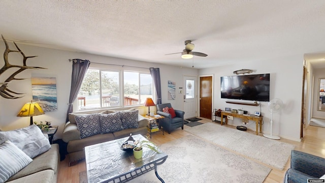 living room featuring light wood-type flooring, a textured ceiling, and ceiling fan