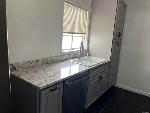 kitchen with light stone counters, sink, and stainless steel dishwasher