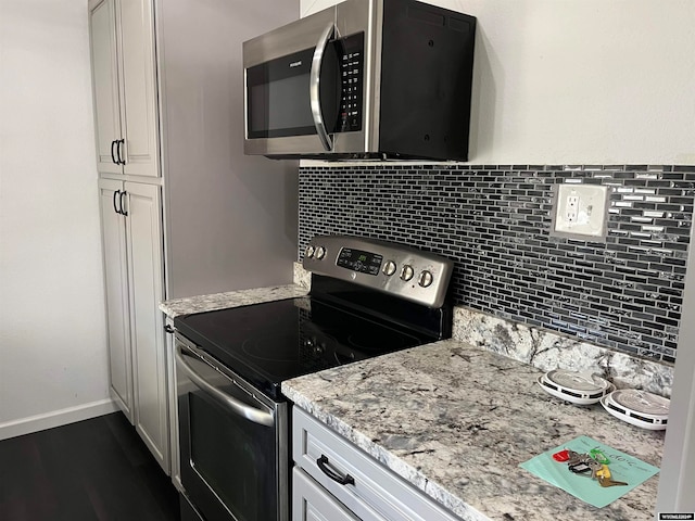 kitchen featuring stainless steel appliances, white cabinets, light stone counters, and tasteful backsplash