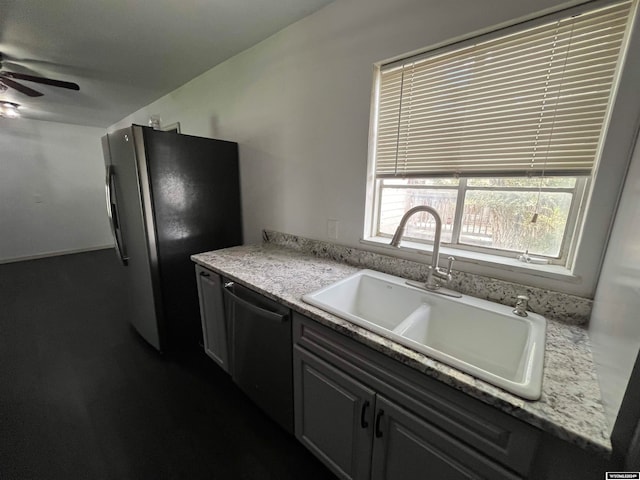 kitchen featuring ceiling fan, appliances with stainless steel finishes, light stone counters, and sink