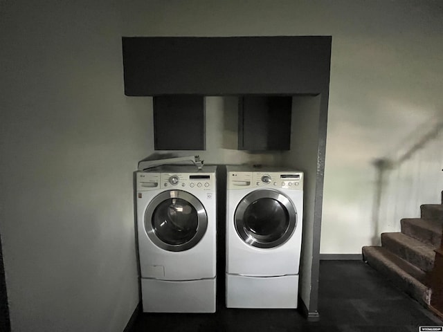 clothes washing area with separate washer and dryer and cabinets