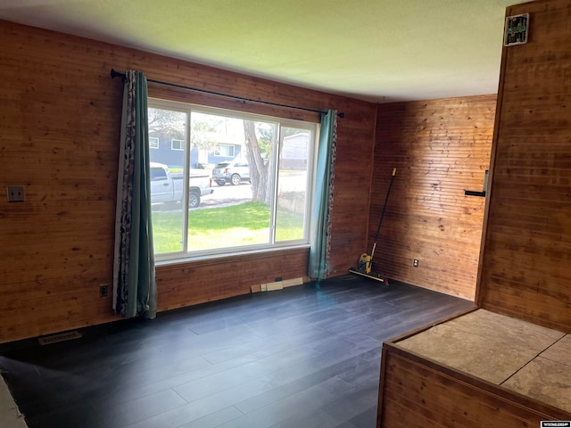 unfurnished room featuring wood walls and dark wood-type flooring