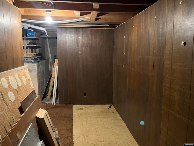 basement featuring wood walls and light parquet flooring