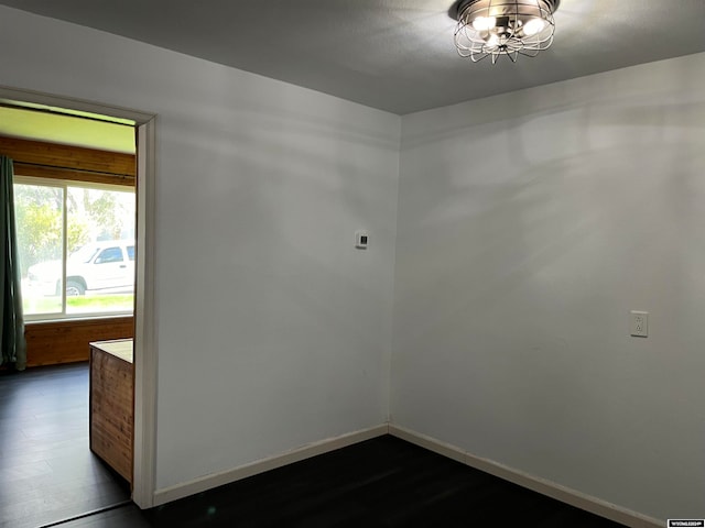 spare room with an inviting chandelier and hardwood / wood-style floors