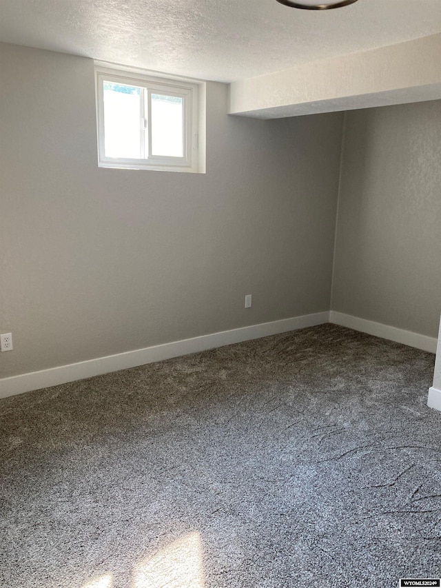 basement with carpet flooring, baseboards, and a textured ceiling