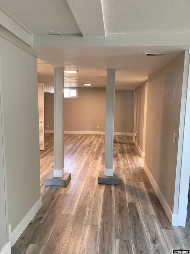 basement featuring a textured ceiling and hardwood / wood-style floors