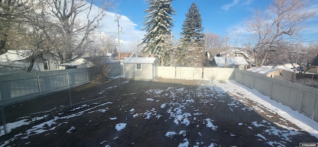 view of yard with a fenced backyard, a storage unit, and an outbuilding