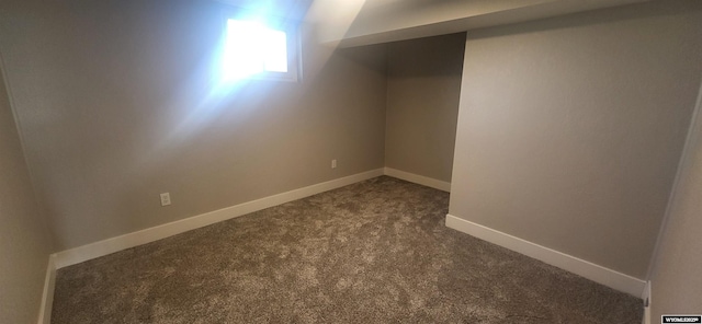 basement with baseboards and dark carpet