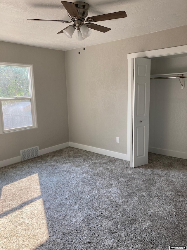 unfurnished bedroom with a textured ceiling, visible vents, baseboards, a ceiling fan, and carpet floors