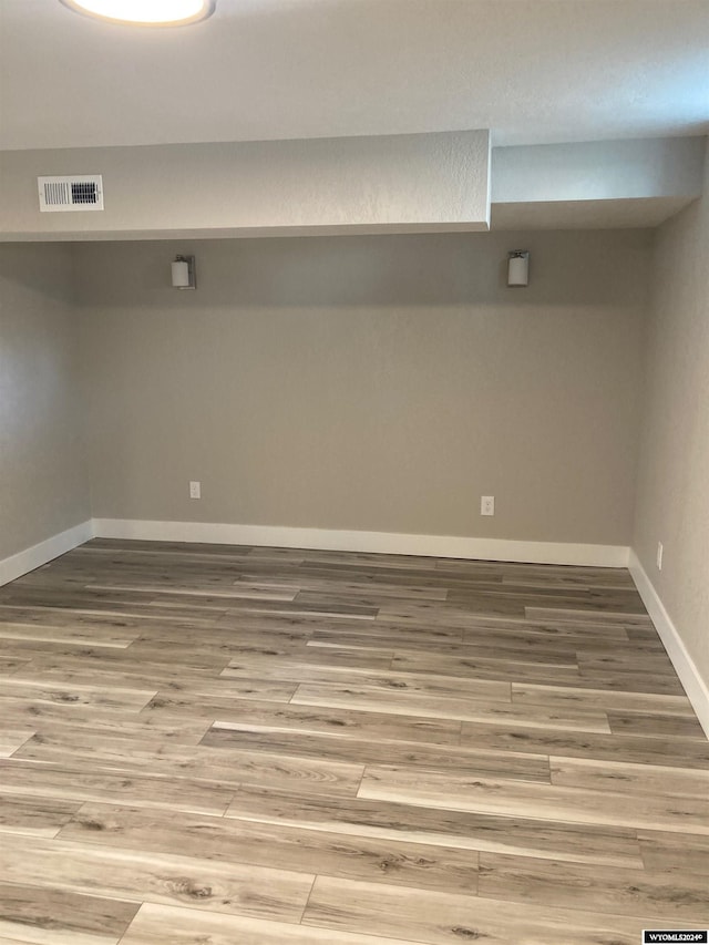 finished below grade area with wood finished floors, baseboards, and visible vents