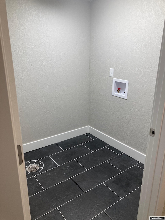 laundry area featuring baseboards, laundry area, dark tile patterned floors, and hookup for a washing machine
