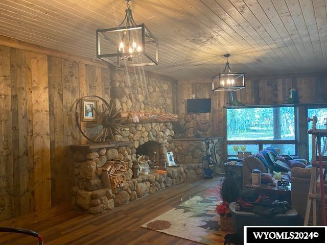 living room featuring hardwood / wood-style flooring, wood ceiling, wood walls, and a notable chandelier