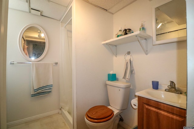 bathroom featuring a shower, a drop ceiling, vanity, and toilet