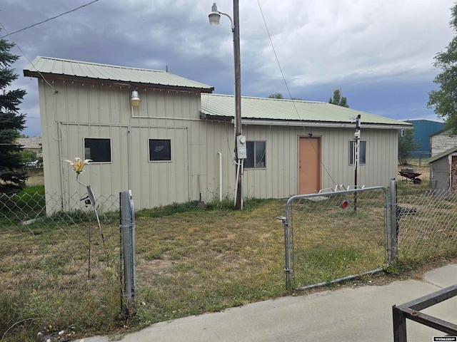 exterior space featuring a lawn, a gate, fence, board and batten siding, and metal roof