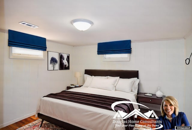 bedroom featuring wooden walls and hardwood / wood-style floors