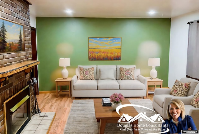 living room with a brick fireplace and light wood-type flooring