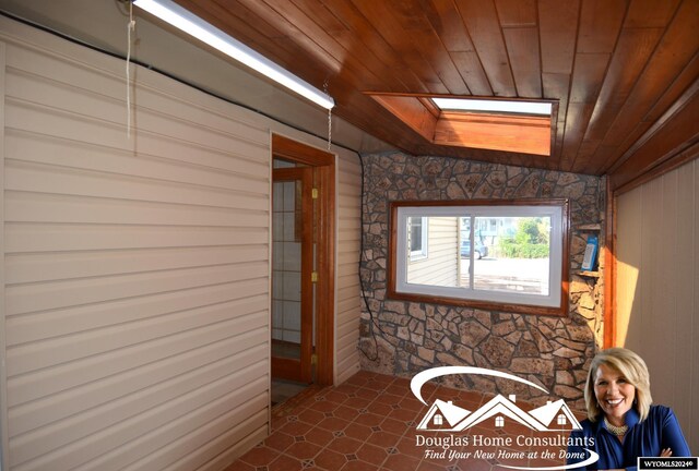 interior space with wood ceiling, wood walls, and a skylight