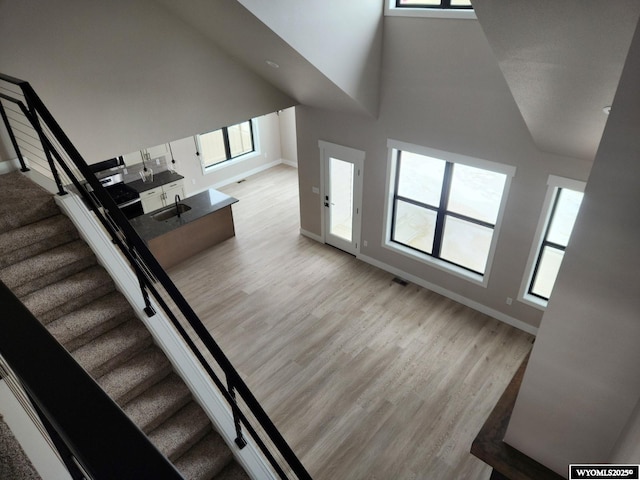 staircase featuring sink, high vaulted ceiling, and hardwood / wood-style flooring