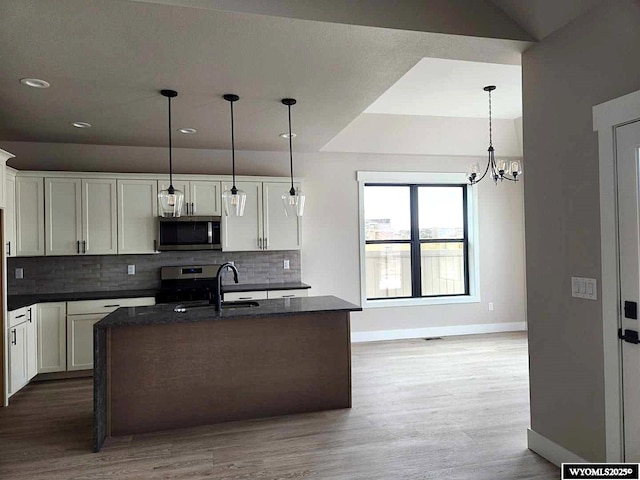 kitchen featuring an island with sink, appliances with stainless steel finishes, and white cabinetry