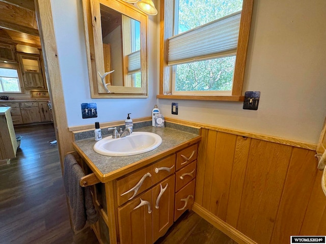 bathroom featuring wood-type flooring, vanity, wood walls, and a wealth of natural light