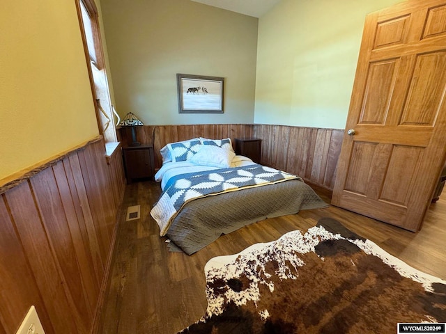 bedroom featuring wooden walls and hardwood / wood-style flooring