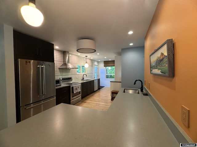 kitchen featuring wall chimney exhaust hood, stainless steel appliances, backsplash, and sink