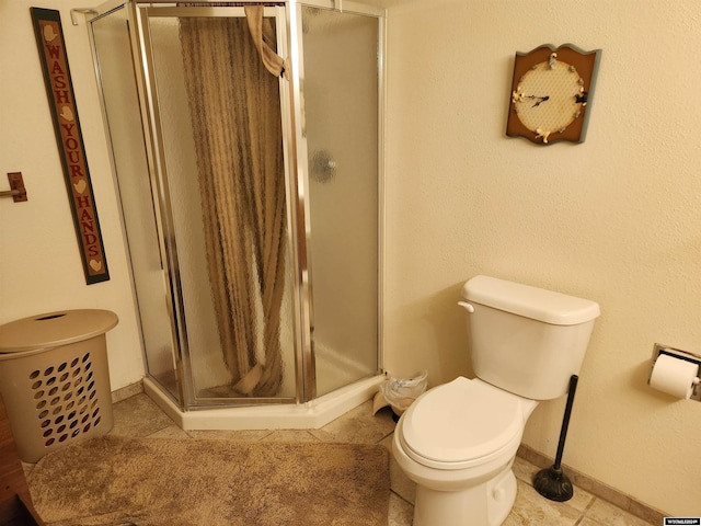 bathroom with tile patterned flooring, toilet, and a shower with door