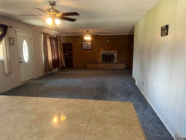 foyer with a textured ceiling, tile patterned flooring, ceiling fan, and a brick fireplace