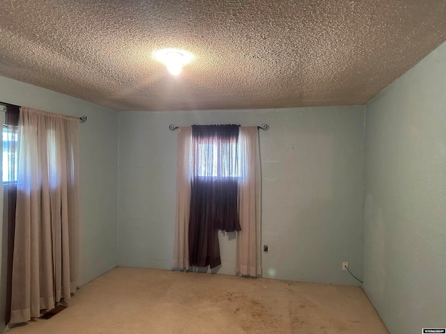 carpeted spare room with a textured ceiling