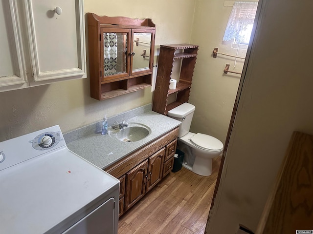 bathroom with hardwood / wood-style floors, vanity, toilet, and washer / dryer