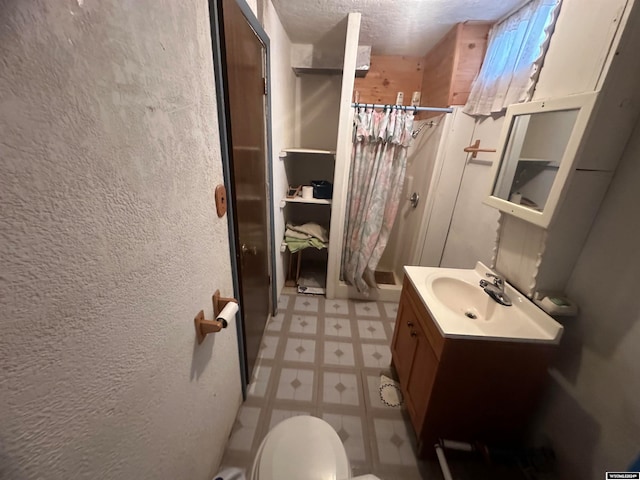 bathroom with a shower with curtain, vanity, toilet, and a textured ceiling