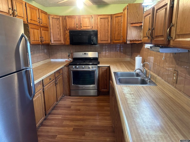 kitchen featuring sink, decorative backsplash, stainless steel appliances, dark hardwood / wood-style flooring, and ceiling fan