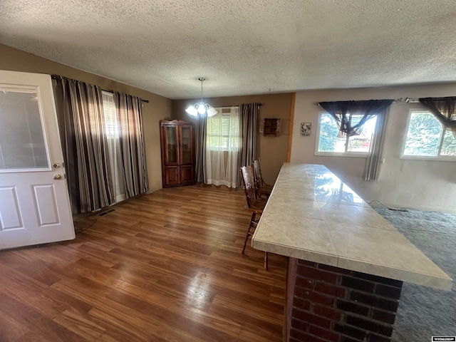 dining area with a textured ceiling, dark hardwood / wood-style floors, and a notable chandelier