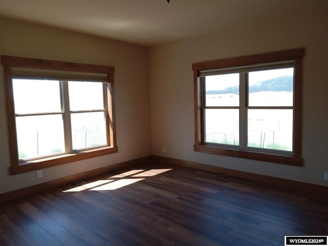 unfurnished room with plenty of natural light, dark hardwood / wood-style flooring, and a mountain view