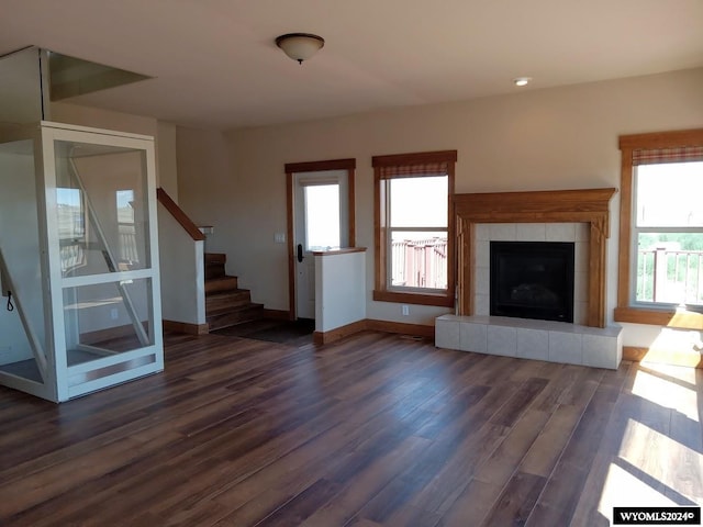 unfurnished living room featuring dark wood-type flooring and a tiled fireplace