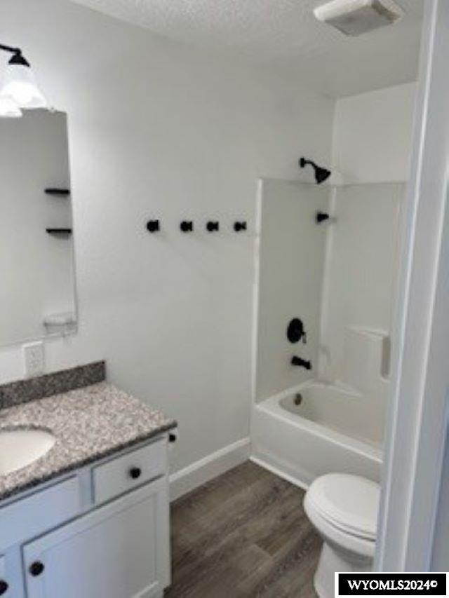 full bathroom with bathtub / shower combination, wood-type flooring, a textured ceiling, vanity, and toilet