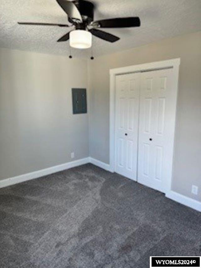 207 W Walnut Sts, Lyman, WY 82937 - unfurnished bedroom with dark carpet, electric panel, baseboards, a closet, and a textured ceiling