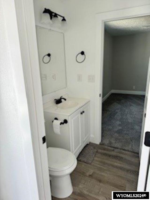 bathroom with vanity, toilet, and hardwood / wood-style flooring