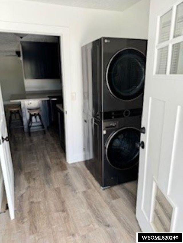 clothes washing area featuring stacked washer / dryer and light wood-type flooring