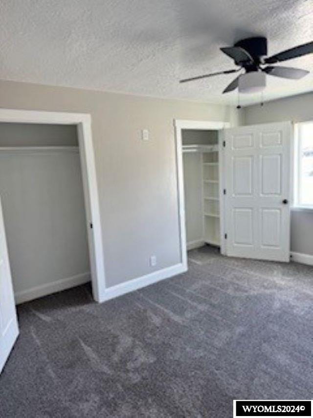 unfurnished bedroom featuring a textured ceiling, dark colored carpet, and ceiling fan