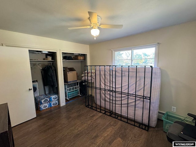 bedroom featuring a baseboard radiator, ceiling fan, dark wood-type flooring, and multiple closets