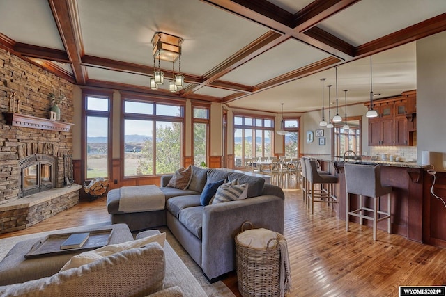 living room featuring coffered ceiling, a mountain view, light hardwood / wood-style flooring, and a fireplace