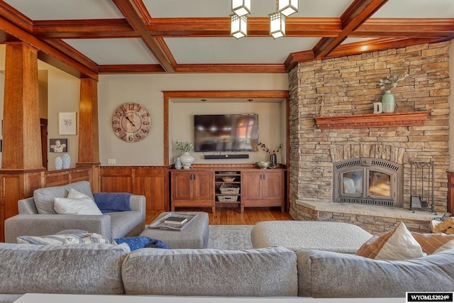 living room featuring beamed ceiling, coffered ceiling, hardwood / wood-style flooring, and a stone fireplace