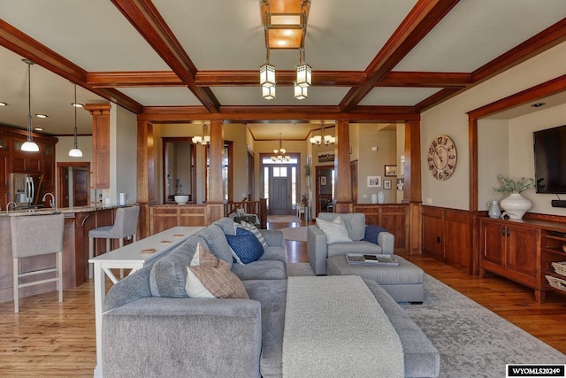 living room with a notable chandelier, light wood-type flooring, beam ceiling, and coffered ceiling