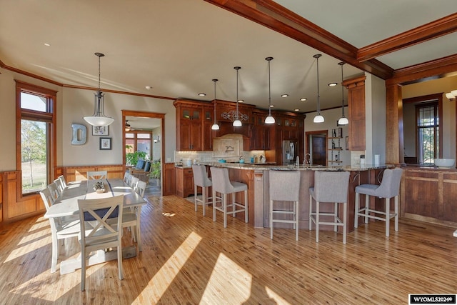 kitchen with pendant lighting, light wood-type flooring, kitchen peninsula, and stone countertops