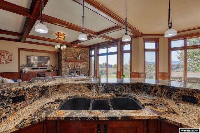 kitchen with a fireplace, coffered ceiling, sink, and pendant lighting