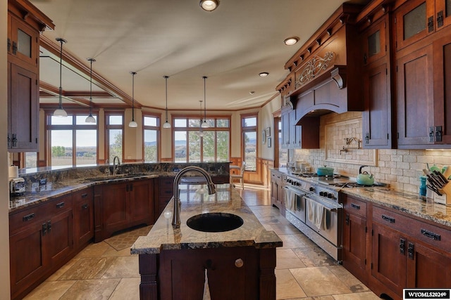 kitchen featuring a center island with sink, sink, high end stainless steel range, and a wealth of natural light