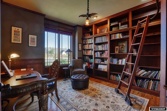 office area with wood-type flooring, wood walls, and crown molding