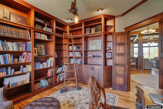 living area featuring light wood-type flooring, ornamental molding, and a notable chandelier