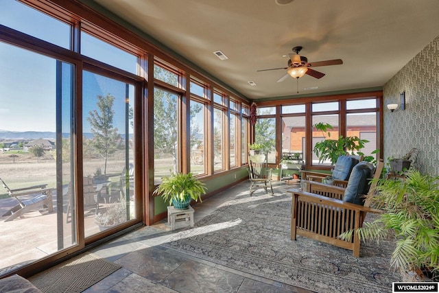 sunroom / solarium featuring a mountain view, ceiling fan, and plenty of natural light